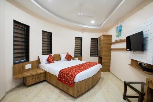 a bedroom with a bed and a flat screen tv at Hotel Balaji Palace in Porbandar