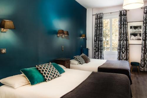2 letti in una camera con pareti blu di Hotel Mirabeau a Tours