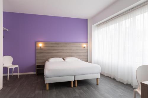 a bedroom with a white bed and a purple wall at BRIT HOTEL CONFORT NEVERS Centre Gare in Nevers