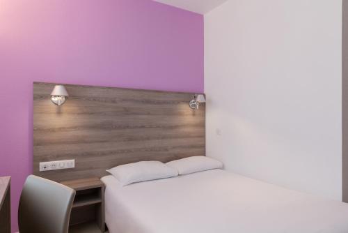 a bedroom with a bed and a desk and purple walls at BRIT HOTEL CONFORT NEVERS Centre Gare in Nevers