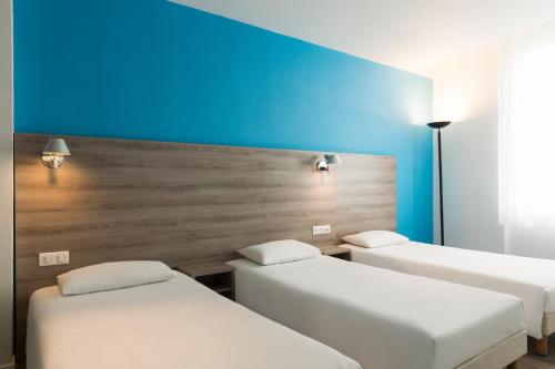 a room with three beds and a blue wall at The Originals City, Hôtel Nevers Centre Gare (Inter-Hotel) in Nevers