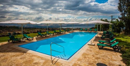 a large swimming pool with chairs and umbrellas at Vered Hagalil Holiday Village Hotel in Chorazim
