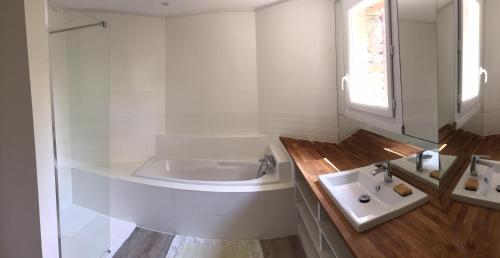 een witte badkamer met een bad en een wastafel bij L'Oursiere in Bédouès