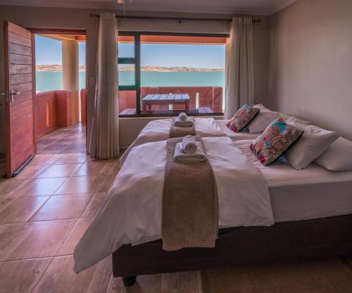a bedroom with a large bed with a view of the ocean at Island Cottage Guesthouse in Lüderitz