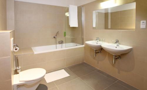 a bathroom with two sinks and a tub and a toilet at Hotel Agnes in Bohdaneč