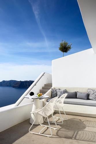 a white patio with a table and chairs on a boat at Filotera Suites in Oia