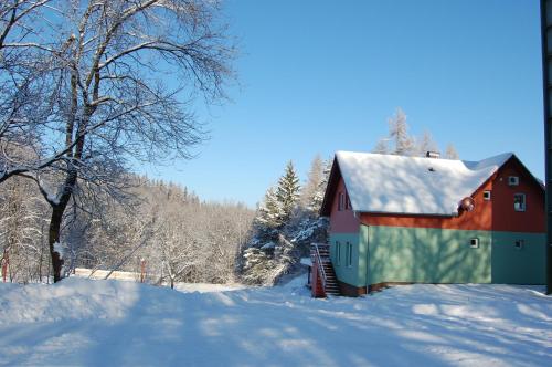 a red and green barn in the snow at Penzion u můstku Jiřího Rašky in Trojanovice