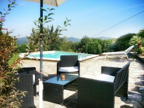 un patio con 2 sedie, un tavolo e una piscina di Belvilla by OYO Villa Ribattolino a Sasso Pisano