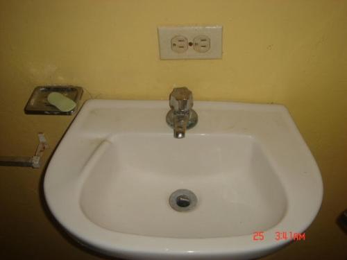 a white sink in a bathroom with two eyes on the wall at Dre Broeders Apartments Juan Dolio in Juan Dolio