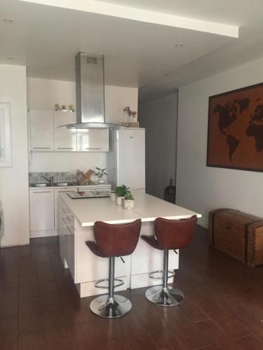 une cuisine avec un comptoir et deux tabourets de bar dans l'établissement T3 proche Castillet, à Perpignan
