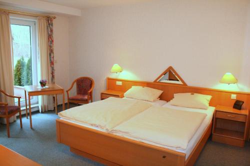 Schlafzimmer mit einem Bett, einem Schreibtisch und einem Tisch in der Unterkunft Hotel Haus Hellhohl in Brilon
