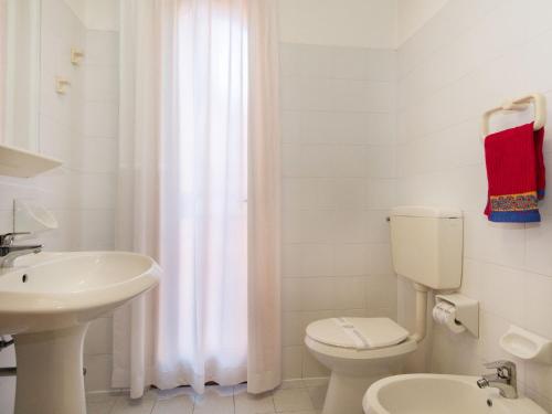 a white bathroom with a toilet and a sink at Bungalow in Po Delta Park with Beach Access in Lido di Spina