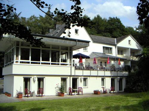 een groot wit gebouw met tafels en stoelen ervoor bij Hotel Haus Hellhohl Garni in Brilon