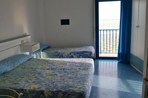 een slaapkamer met 2 bedden en een deur naar een balkon bij Hotel Playa e Mare Nostrum in Caorle