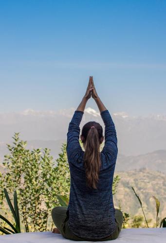 a woman doing yoga on top of a mountain at The Lapsi Tree in Nagarkot