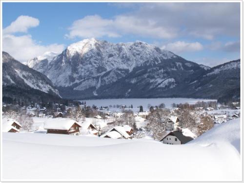 a snow covered mountain range with a town and houses in the foreground at Ferienwohnung Haus Einhirn in Altaussee