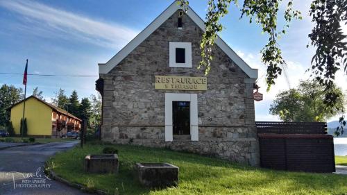 a small stone building with a sign on it at Hotel Jestřábí in Černá v Pošumaví