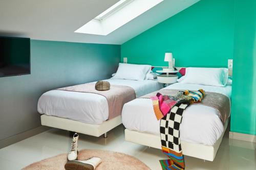 two beds in a room with blue and green walls at Hotel Freedom in Madrid