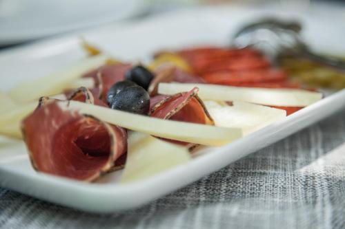 a plate of food with meat and cheese and olives at Apartment Castel in Bale