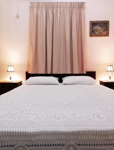 a bedroom with a large white bed with two lamps at Mezapos Villa Makrina in Mézapos