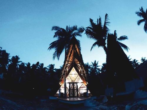 a small building with palm trees on a beach at Dahun Villas Siargao in General Luna