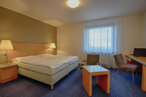 a hotel room with a bed and a desk and a window at Hotel Henrietta in Prague