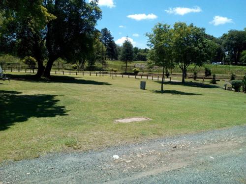 a field of grass with trees and a fence at Sabie River Camp in Sabie