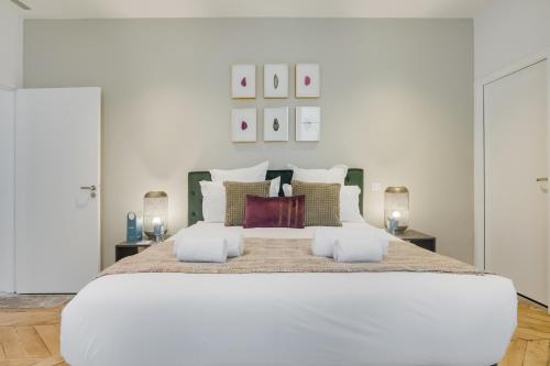 パリにあるSweet Inn - Bonne Nouvelleの白いベッドルーム(大きな白いベッド、ランプ2つ付)