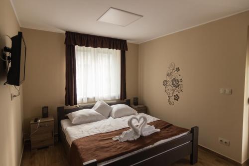 a bedroom with a bed with a swan on it at Cuha-gyöngye Apartmanház in Zirc