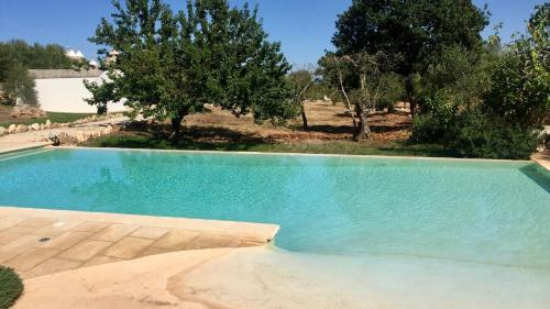 an empty swimming pool with trees in the background at Trulli Masseria Donno Santo in Ceglie Messapica