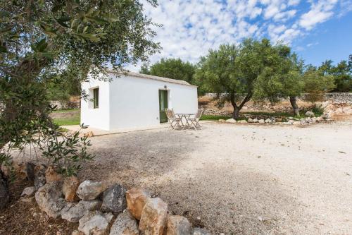 a white building with a table and chairs in a yard at Trulli Masseria Donno Santo in Ceglie Messapica