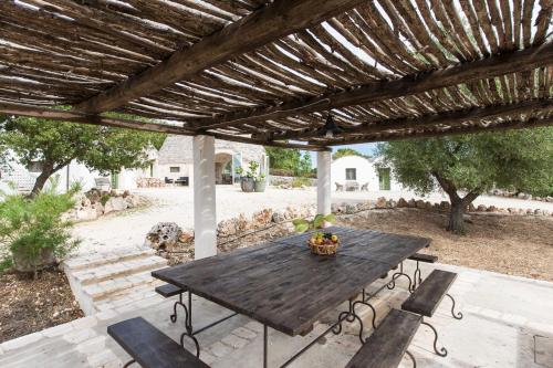 a wooden table and chairs under a wooden pergola at Trulli Masseria Donno Santo in Ceglie Messapica