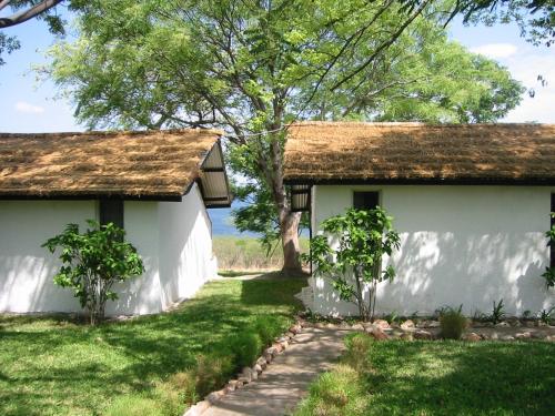 two white buildings with a tree in the yard at Musungwa Safari Lodge in Shanjungu