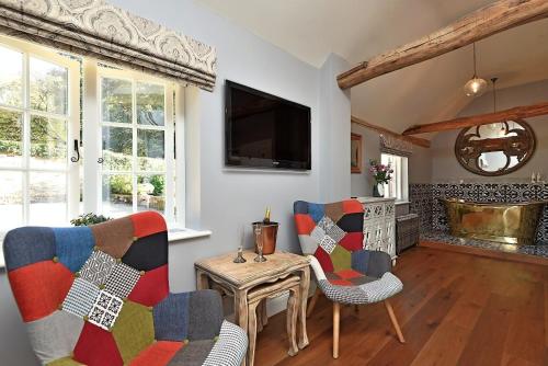 長梅爾福德的住宿－The Mill, Long Melford，客厅配有两把椅子、一张桌子和一台电视