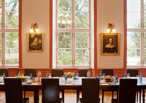 a room with tables and chairs and windows at Schlosshotel Ziethen in Kremmen