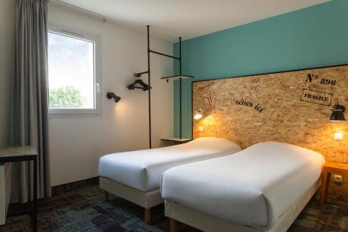 a hotel room with two beds and a window at The Originals Access, Hôtel Clermont-Ferrand Nord in Châteaugay