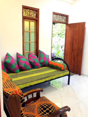 a bench with colorful pillows sitting in a room at Monara Backpacker Inn Unawatuna in Unawatuna