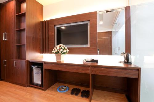 ein Badezimmer mit einem Waschtisch, einem TV und einem Spiegel in der Unterkunft Prague Hotel in Ho-Chi-Minh-Stadt
