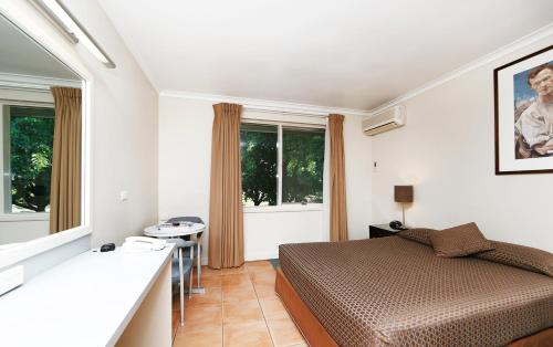 a bedroom with a bed and a table in it at Forrest Hotel & Apartments in Canberra