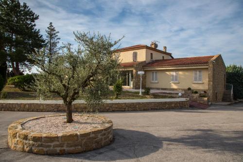 a tree in a stone circle in front of a house at Hôtel Castel Saint Anne in Le Castellet