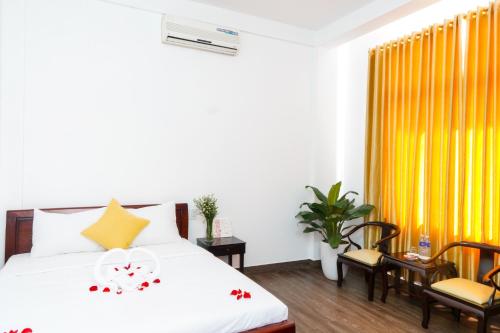 um quarto com uma cama e cadeiras e uma cortina amarela em Hue Royal Hotel em Hue