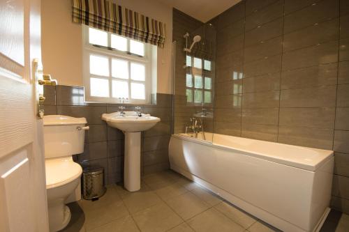 a bathroom with a tub and a sink and a toilet at Tissington Cottage- Darwin Lake Holiday Village in Matlock