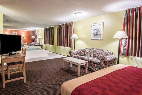 a hotel room with a bed and a couch and a tv at Rodeway Inn Willamette River in Corvallis