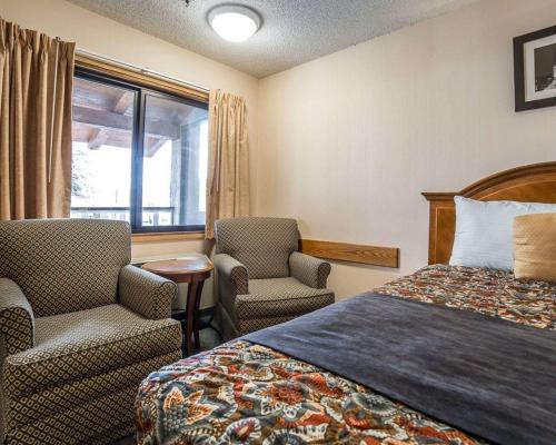 a hotel room with a bed and two chairs and a window at Rodeway Inn in Baker City
