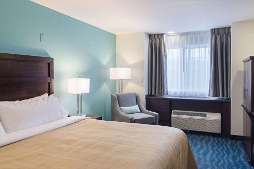 a hotel room with a bed and a chair and a window at Quality Inn Seaside in Seaside