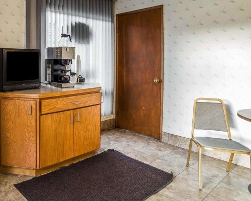 Cette chambre dispose d'une télévision, d'une chaise et d'une table. dans l'établissement Rodeway Inn & Suites, à Arlington
