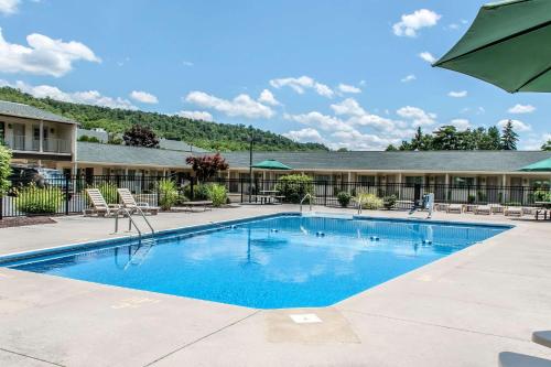 a large swimming pool with chairs and an umbrella at Quality Inn in Bedford