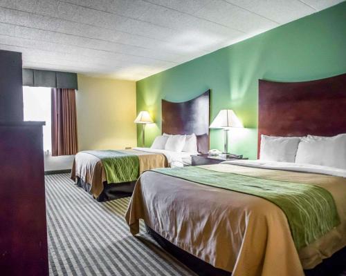 two beds in a hotel room with green walls at Quality Inn Mill Hall - Lamar in Clintondale