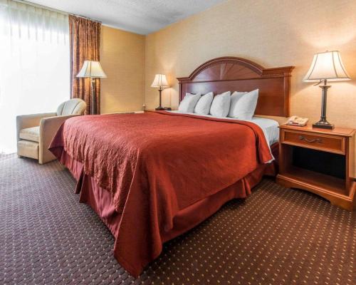 a hotel room with a large bed with a red blanket at Quality Inn & Suites Erie near Casino in Erie