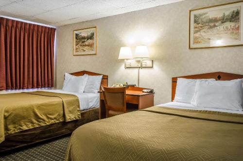 una camera d'albergo con 2 letti e una scrivania di Rodeway Inn State College - near University a State College